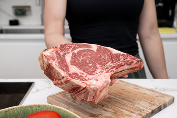 Fresh Ribeye Steak Held by Individual in a Bright Modern Kitchen Environment
