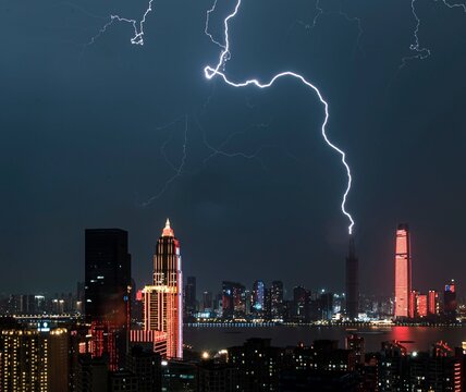 Lightning over illuminated city skyline at night. - Powered by Adobe
