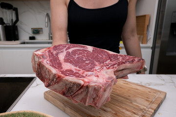 Close-Up of a Raw Ribeye Steak Held by a Woman in a Contemporary Kitchen Setting