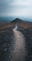A rugged trail ascends a mountain ridge under a muted sky