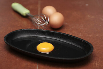 
A single egg yolk rests in a small black skillet