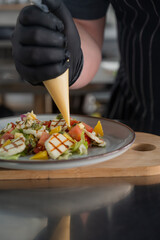 The chef seasons the salad with sauce. 