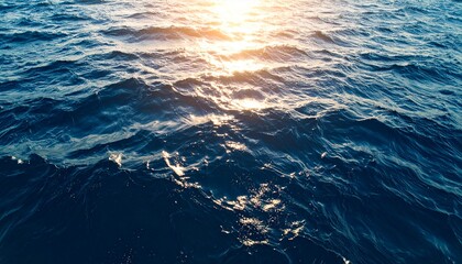 Ocean water surface at sunset with golden sunlight reflections on gentle waves. Calm, serene seascape background perfect for nature, travel, and design projects.