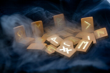 Gray thick smoke around wooden runes on a dark background close-up	
