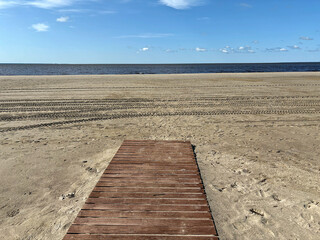 Wooden walkway and tire tracks on a deserted beach