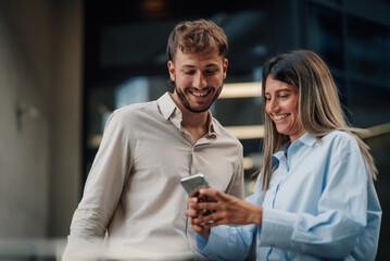Business partners smiling and using a smartphone in modern office building