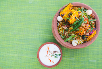 Vegetable Paneer Biryani in an earthen bowl served with Yoghurt raita and condiments, Indian restaurant in Dubai, Vegetarian plant based dinner recipe