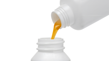 Orange liquid being poured from white plastic bottle into container on the transparent background, closeup of viscous fluid transfer for medical or chemical use