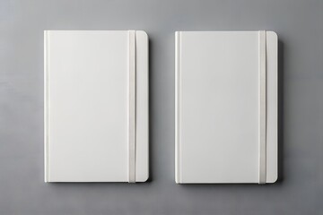 Two blank white notebooks with elastic bands on a gray background