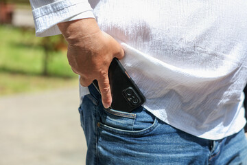 A man is holding a cell phone in his pocket