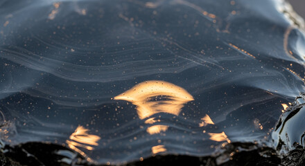 Polished Obsidian Stone with Golden Light Reflections and Subtle Wavy Patterns