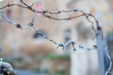Closeup of a barbed wire fence in focus, with a blurry background