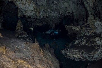 A diver explores a dark, dramatic cave system with stunning rock formations.