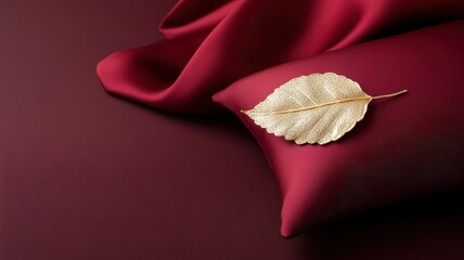Gold filigree leaf on deep burgundy silk pillow, symbolizing luxury.