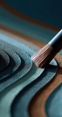 Close-up of a paintbrush applying color to layered, textured surfaces