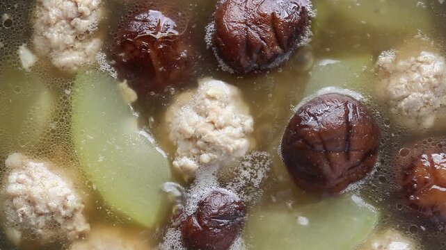 Shiitake mushrooms and minced pork meatball soup with winter melon is cooking in a hot pot. Asian food