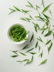 Top view of green tea leaves in white cup with scattered fresh leaves