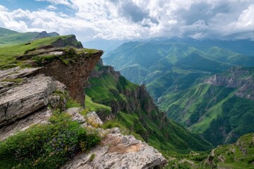 Obraz premium Verdant cliffs a valley and distant mountains under cloudy skies