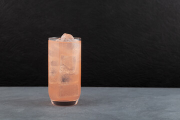 Refreshing cold grapefruit drink with ice cubes. Сold summer cocktail in tall glass. Delicious trendy iced drink