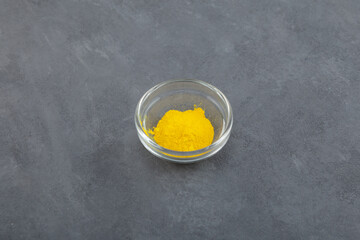 Food additive E104 powder in glass bowl. Quinoline yellow dye, also known as Acid yellow 3. Color index of 47005. Dye is contraindicated in people who are sensitive to aspirin