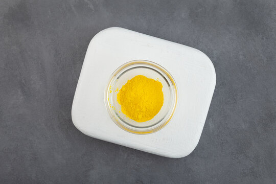 Sample of Food additive E104 powder in glass bowl, top view. Quinoline yellow dye, also known as Food Yellow 13. Color index of 47005. Pigment E104 poses a potential health threat