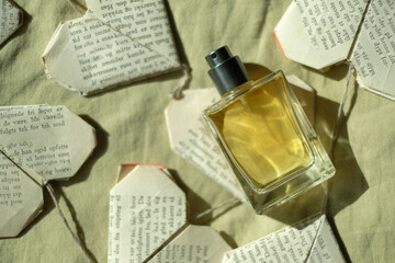 perfume bottle with yellow liquid on a yellow background with paper hearts