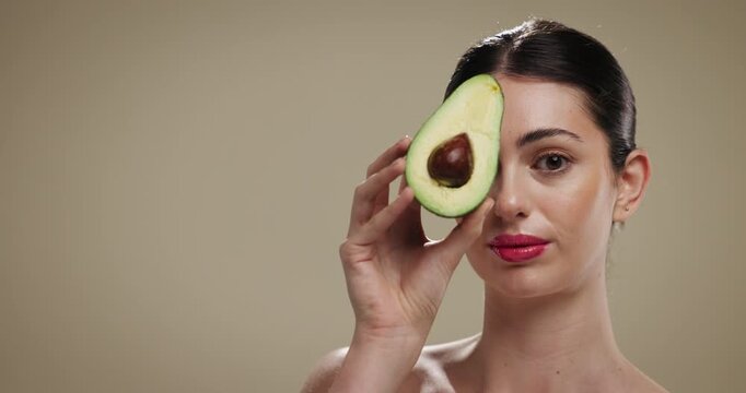 Skincare, natural and face of woman with avocado in studio for beauty, glow or moisturizing benefits. Mockup space, portrait and person with fruit for dermatology with hydration by brown background.
