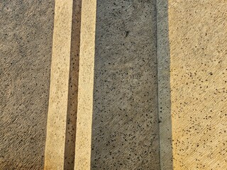 Two yellow road lines on textured asphalt, offering a minimal urban backdrop perfect for transportation themes, travel banners, or cityscape designs