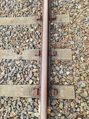 Railway tracks merging in the distance with concrete siding and grass along the edges, symbolizing unity, infrastructure, and direction in transportation