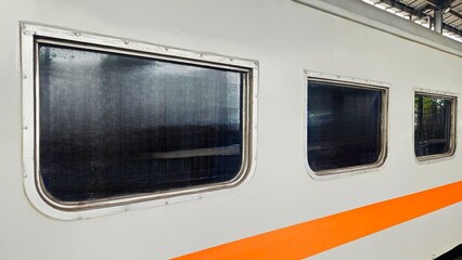 Perspective shot of train windows aligned along the carriage, showing depth and reflection