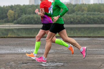 two female athletes running along river embankment marathon race