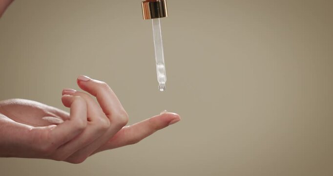 Skincare, pipette and serum on hand for beauty, dermatology or health closeup. Finger, dropper and woman apply cosmetic product or vitamin c for anti aging on studio background with mockup space