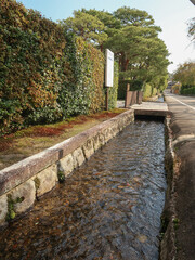 narrow stream aside of sidewalk