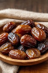 A close-up of a wooden plate stacked with shiny, plump, and slightly wrinkled dried dates