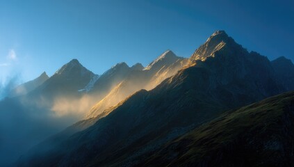 Mountain peaks bathed in golden sunrise light, mist rising from valleys