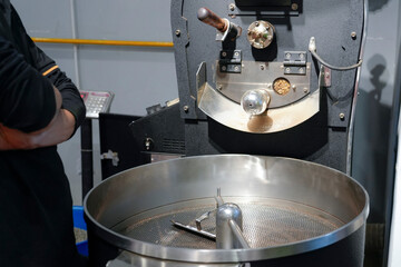 A skilled barista monitors the roasting machine as fresh coffee beans roast to perfection in the cafe. The aroma fills the air, creating a vibrant atmosphere for coffee lovers
