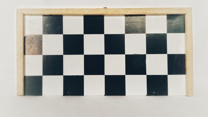 A wooden chess board with a checkered pattern with alternating black and white colors.
