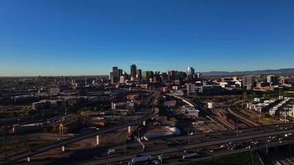 Aerial view of Denver's skyline with roads bustling with vehicles under a clear sky, a vibrant urban landscape, Denver, Denver County, United States.
