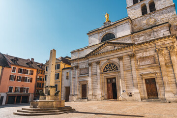 Place Notre Dame with stone Obelisk fountain, lion sculptures, golden cathedral statue and surrounding historic achitectural medieval at Annecy, France