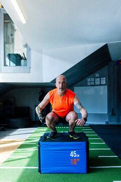 Athlete with prosthetic leg squatting on jump box at gym