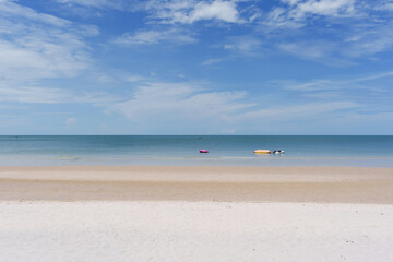 Sandy beach with tropical sea and inflatable boats under bright sky on summer