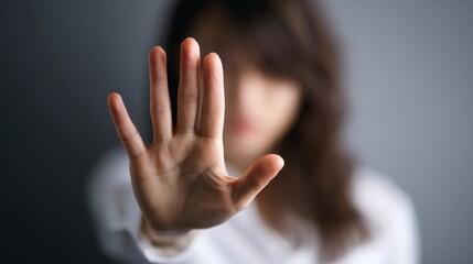 In a calm indoor environment, a woman raises her hand to signal stop as she addresses harassment, visibly expressing defiance and courage against inappropriate behavior