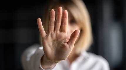 Obraz premium A woman holds up their hand to signal stop. Harassment at work. The setting appears dark, reflecting a serious atmosphere