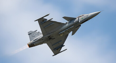 A Swedish JAS 39 Gripen fighter jet performing a maneuver in the sky with clouds.