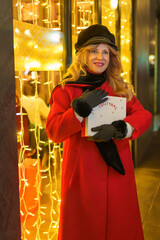 Woman with Christmas gift next to illuminated shop window