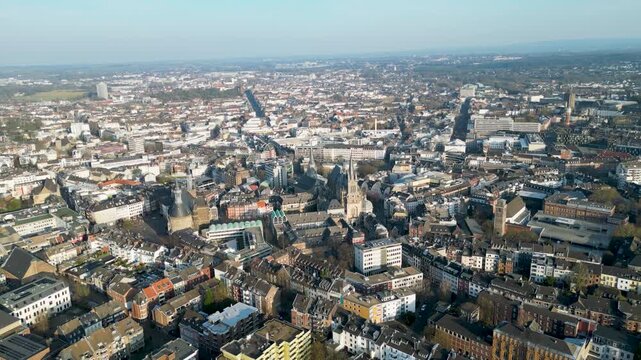 Aerial view of Aachen Cathedral's intricate spires rise amidst the urban tapestry, contrasting with the city's modern buildings, Aachen, North Rhine-Westphalia, Germany.