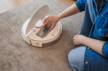 Smart home concept. Woman cleans and puts back filter for launching vacuum cleaner