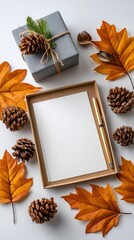 Autumn gift box with blank paper and pen surrounded by leaves and pinecones