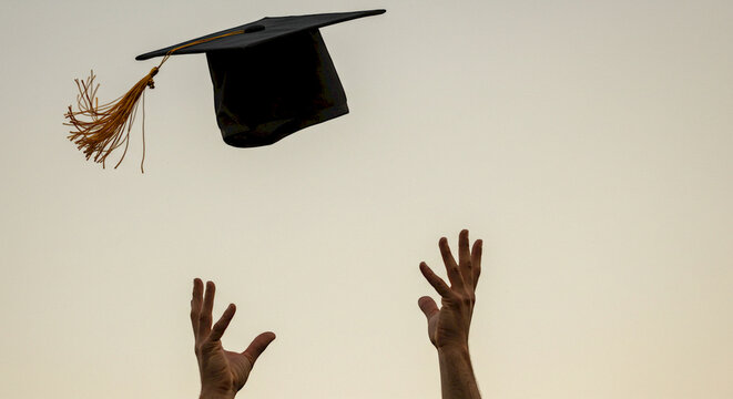 Graduates celebrating by throwing caps into the air at sunset
