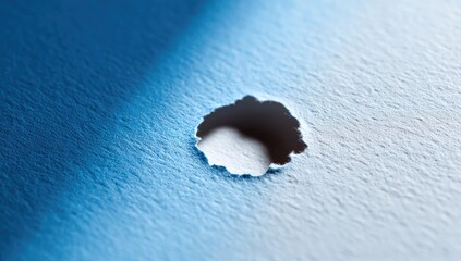 Close-up of a hole punched through textured blue paper